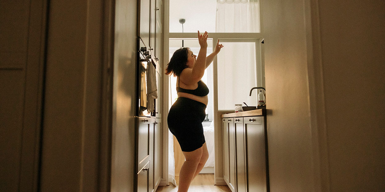 Tjej står i köket och dansar med händerna upp i luften.