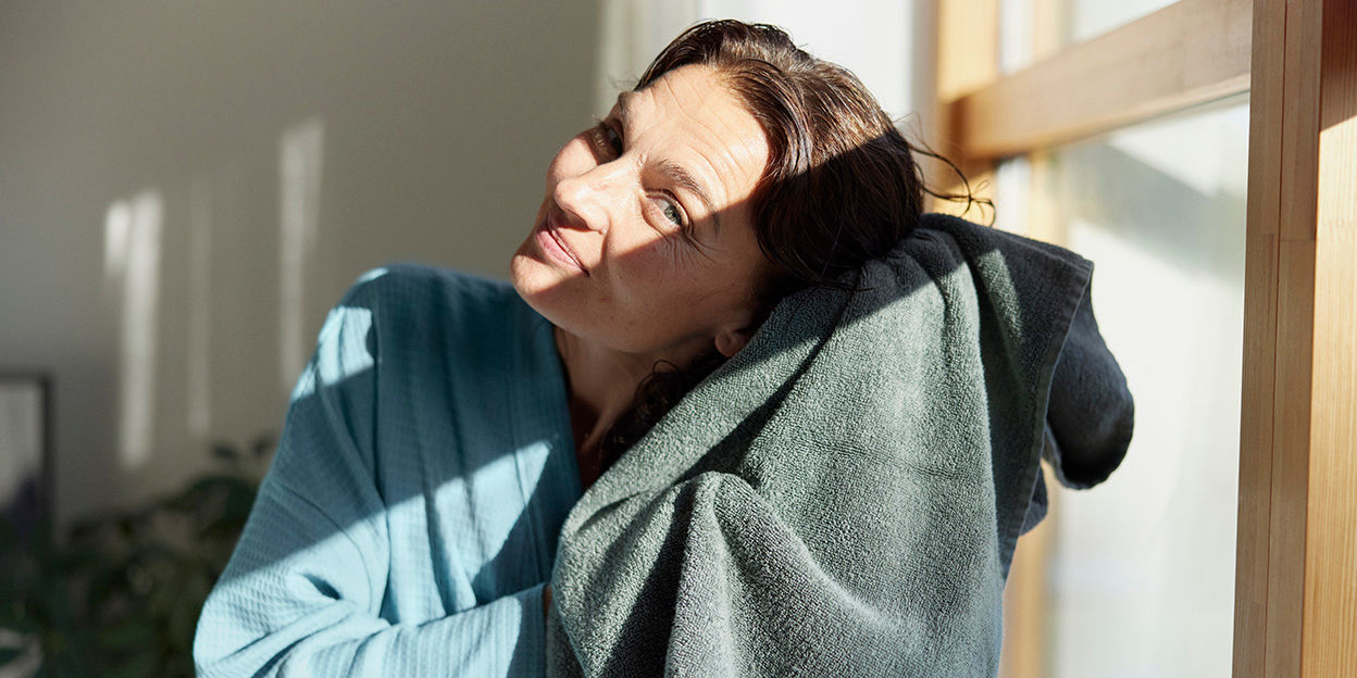 Kvinna tvättar håret. Hon torkar håret med en handduk.