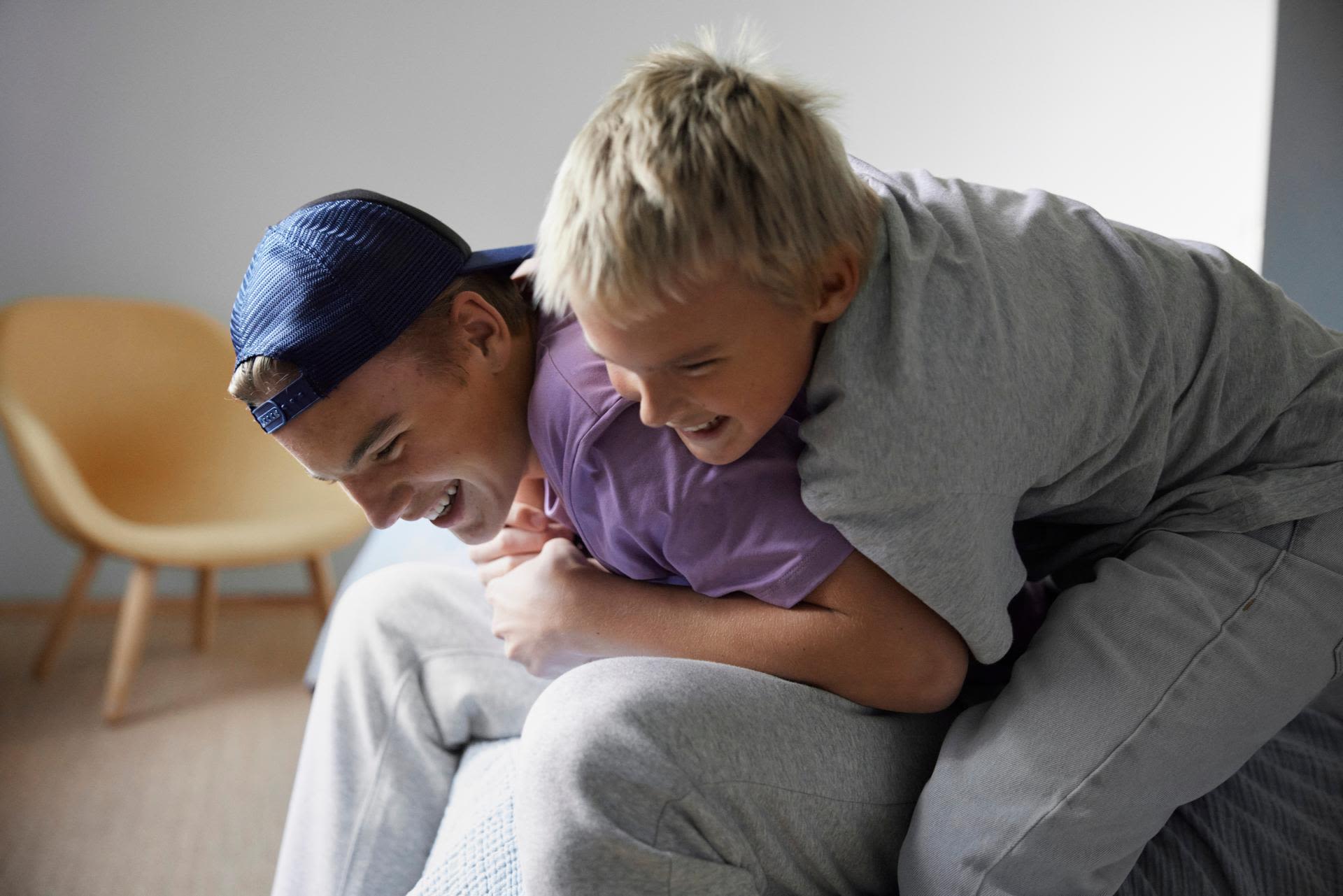 Två tonårsbröder som skojbråkar med varandra och skrattar.
