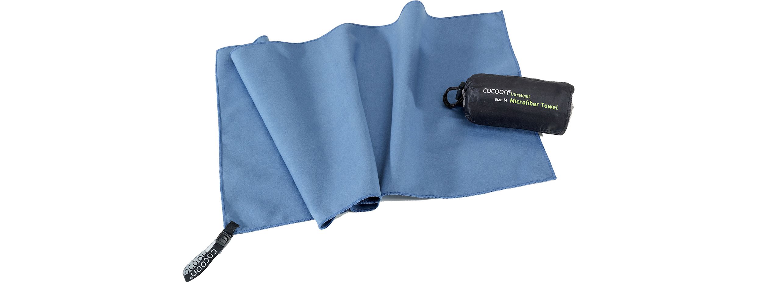 Blå mikrofiberhandduk ligger utvikt med en svart påse märkt "Cocoon Ultralight size M Microfiber Towel" bredvid.