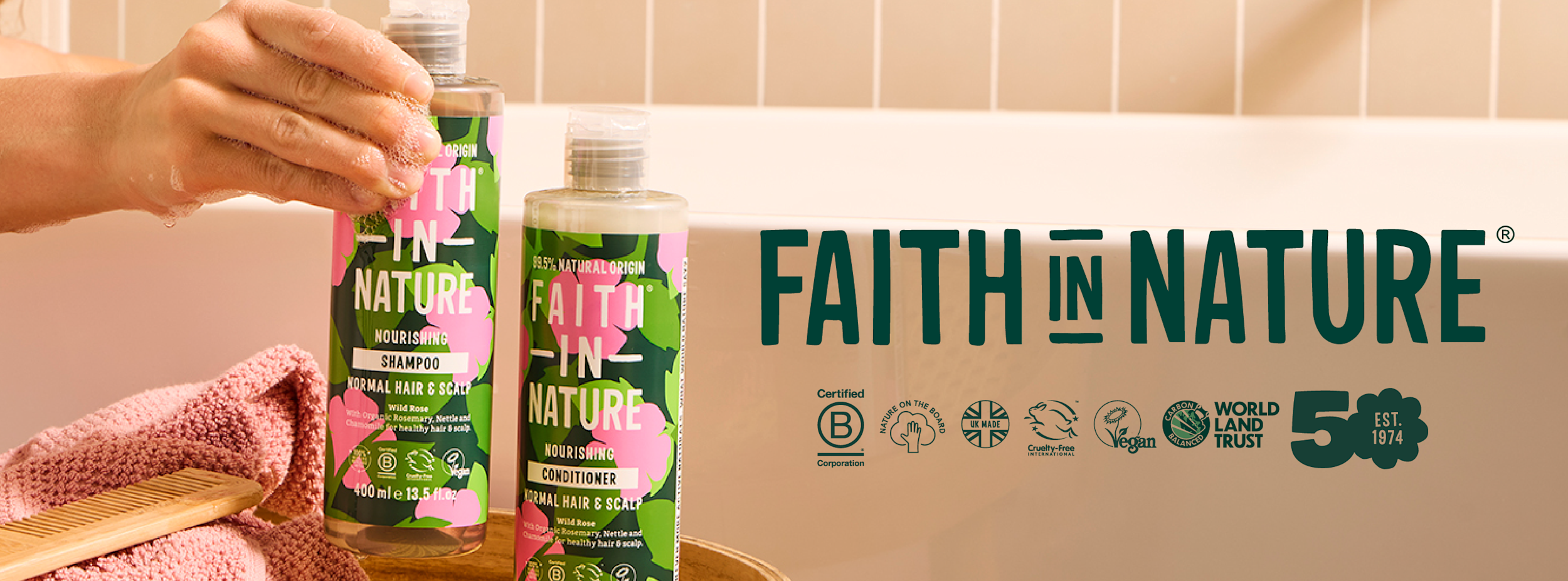En hand håller en flaska Faith In Nature schampo bredvid ett balsam på badkarskanten, med logotyp och certifieringssymboler i bakgrunden.