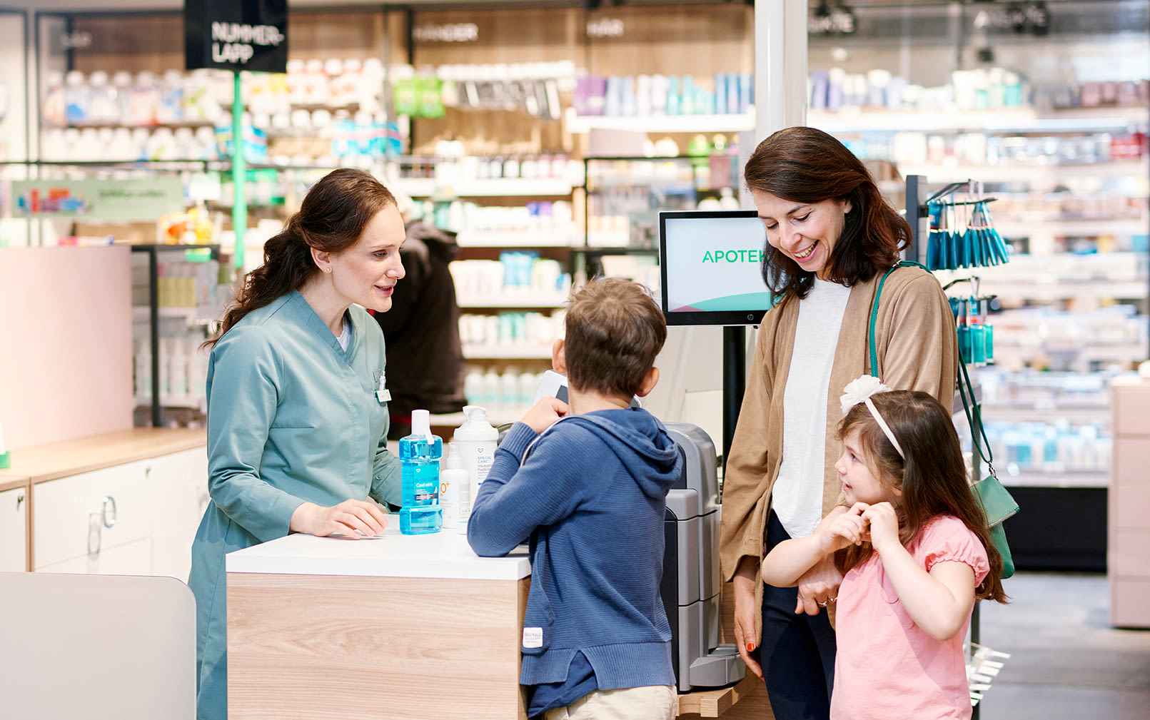 En familj står inne på ett apotek och ska betala vid kassan.
