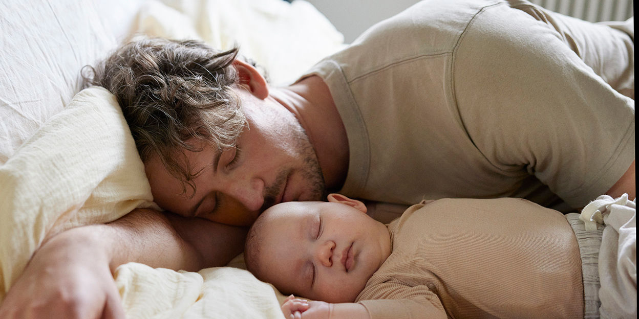 Pappa och bebis sover i sängen. 