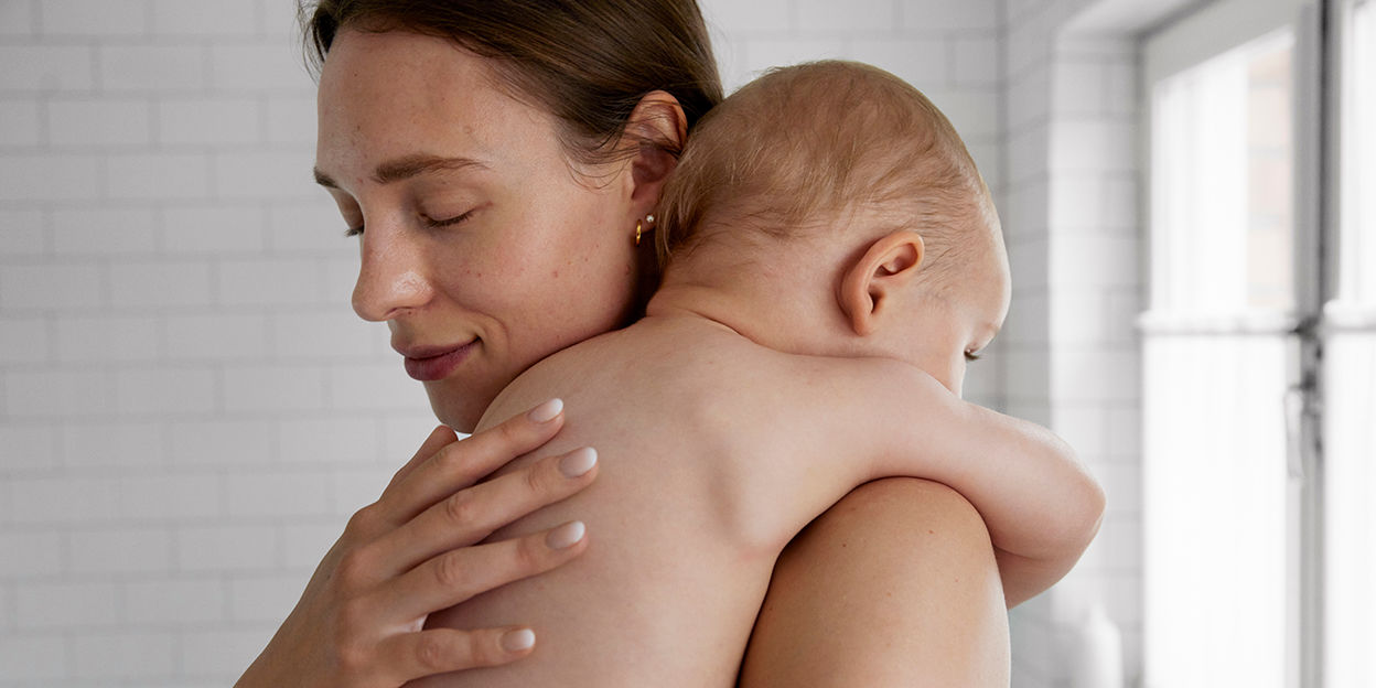 Kvinna håller om bebis i badrummet. 