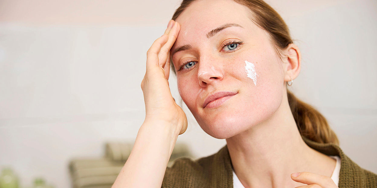 kvinna smörjer in ansiktet med solskydd