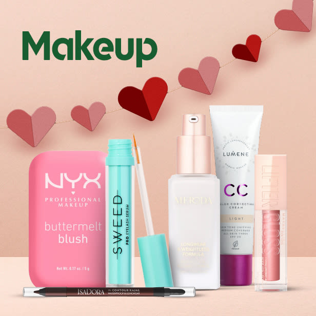 Fem olika sminkprodukter står på en beige yta med en girlang av pappershjärtan i rött och rosa hängande ovanför.