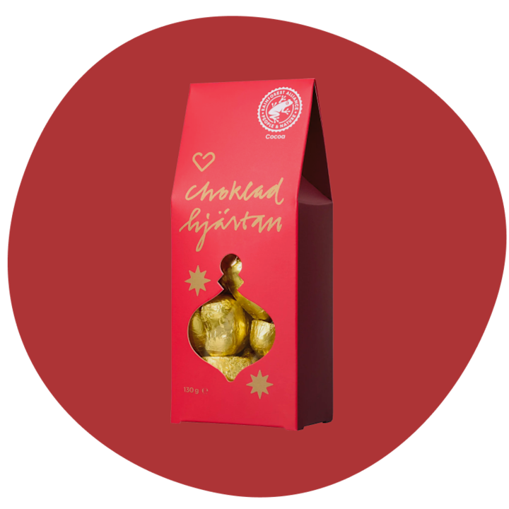 Rött paket med texten "chokladhjärtan" som innehåller guldfärgade hjärtformade chokladbitar mot en röd bakgrund.